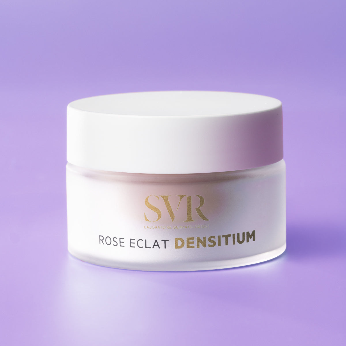 Tarro de crema antiedad SVR Densitium Rose Eclat en envase de vidrio esmerilado con tapa blanca sobre fondo lila.