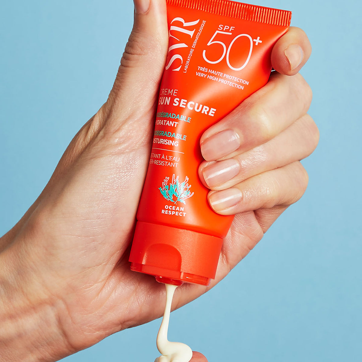 Tubo naranja de crema solar SVR Sun Secure SPF50+ siendo presionado para aplicar una textura cremosa sobre la mano.