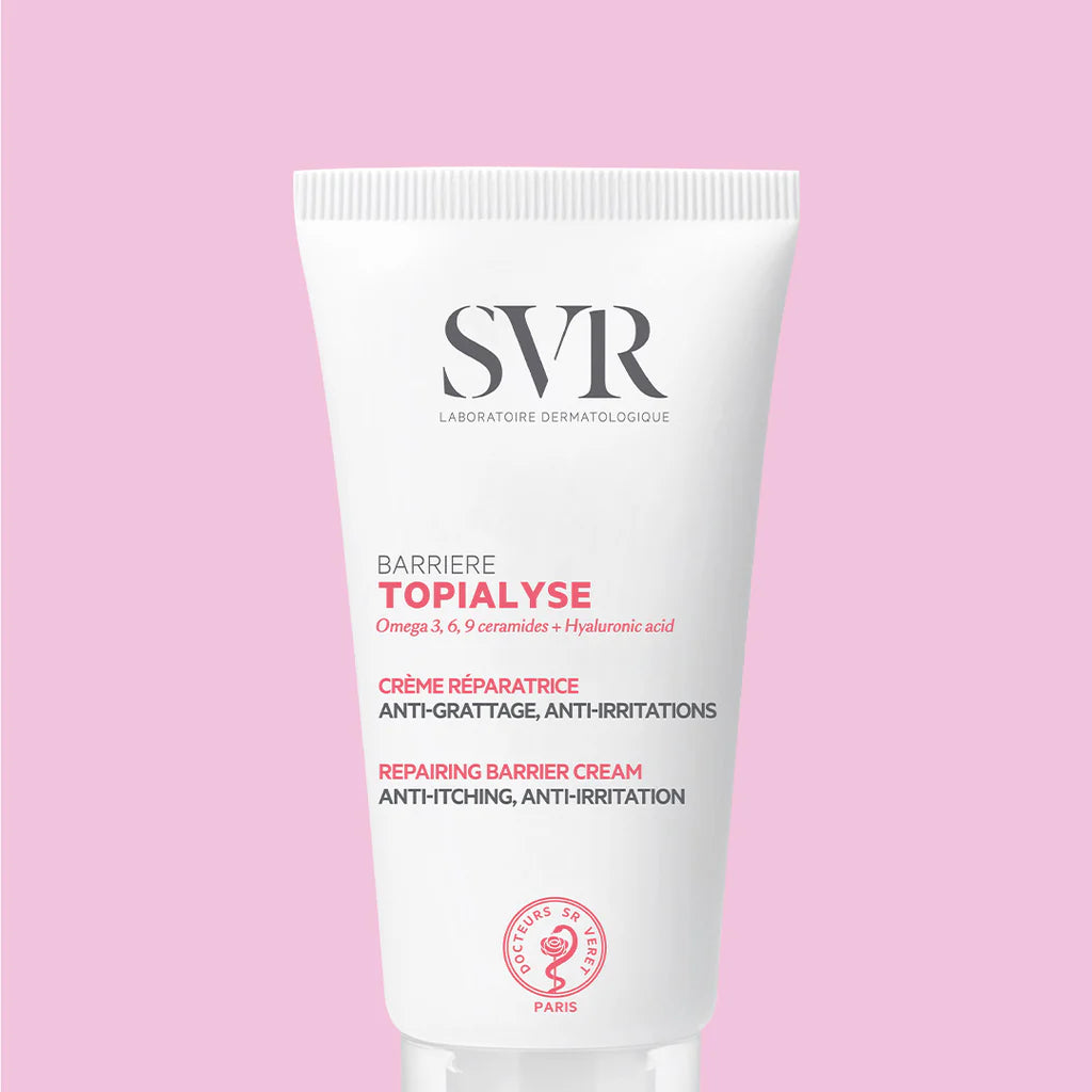 Tubo blanco de crema reparadora SVR Topialyse Barrière con letras rosas y negras sobre un fondo rosa suave.