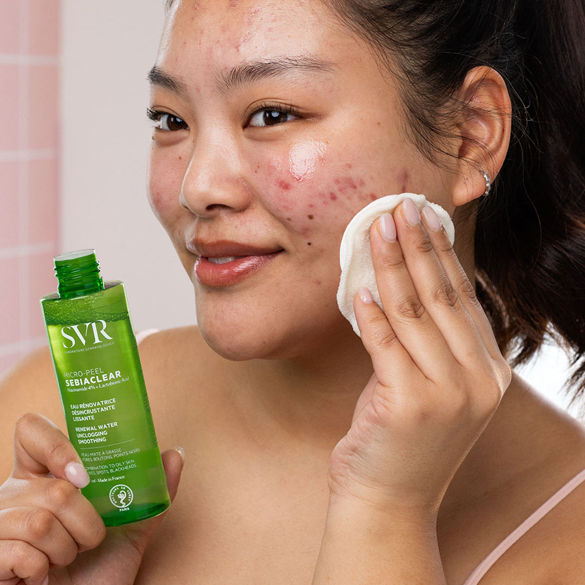 Mujer aplicando SVR Sebiaclear Micro-Peel con un algodón sobre su rostro para tratar imperfecciones y poros.