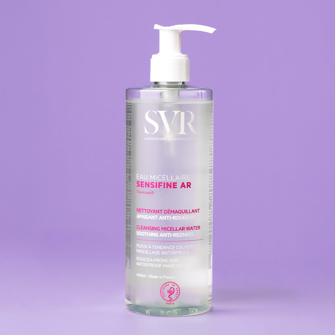 Envase de 400ml de agua micelar SVR Sensifine AR con dosificador blanco sobre fondo morado para pieles con rojeces.