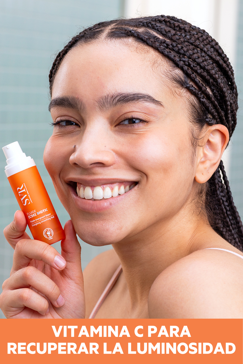 Mujer con piel luminosa sosteniendo el fluido antioxidante SVR [C20] Biotic, tratamiento facial con vitamina C para revitalizar y alisar la piel.