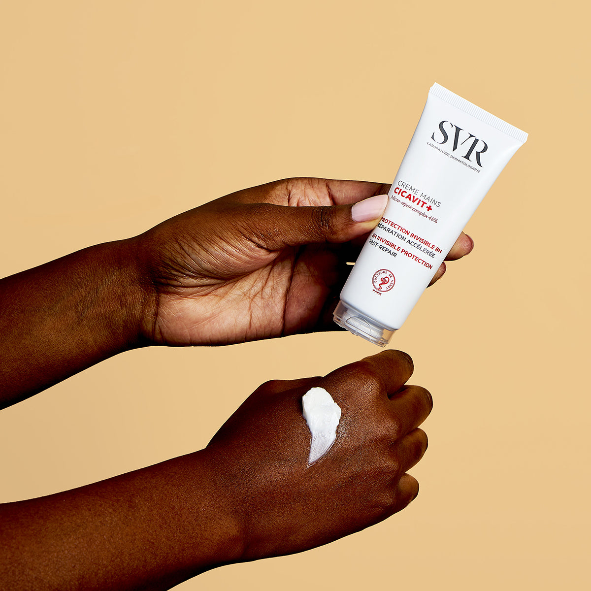 Tubo blanco de crema de manos SVR Cicavit+ siendo aplicado sobre la piel, mostrando la textura cremosa del producto.