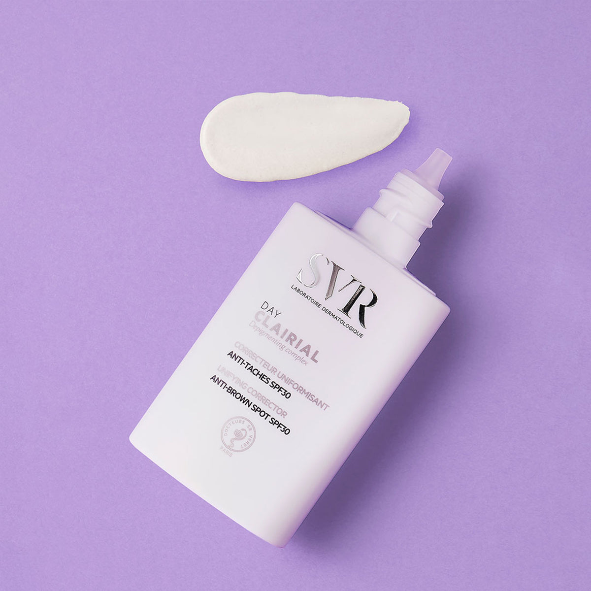 Envase blanco de SVR Clairial Day con crema aplicada sobre fondo lila, corrector antimanchas con SPF30.