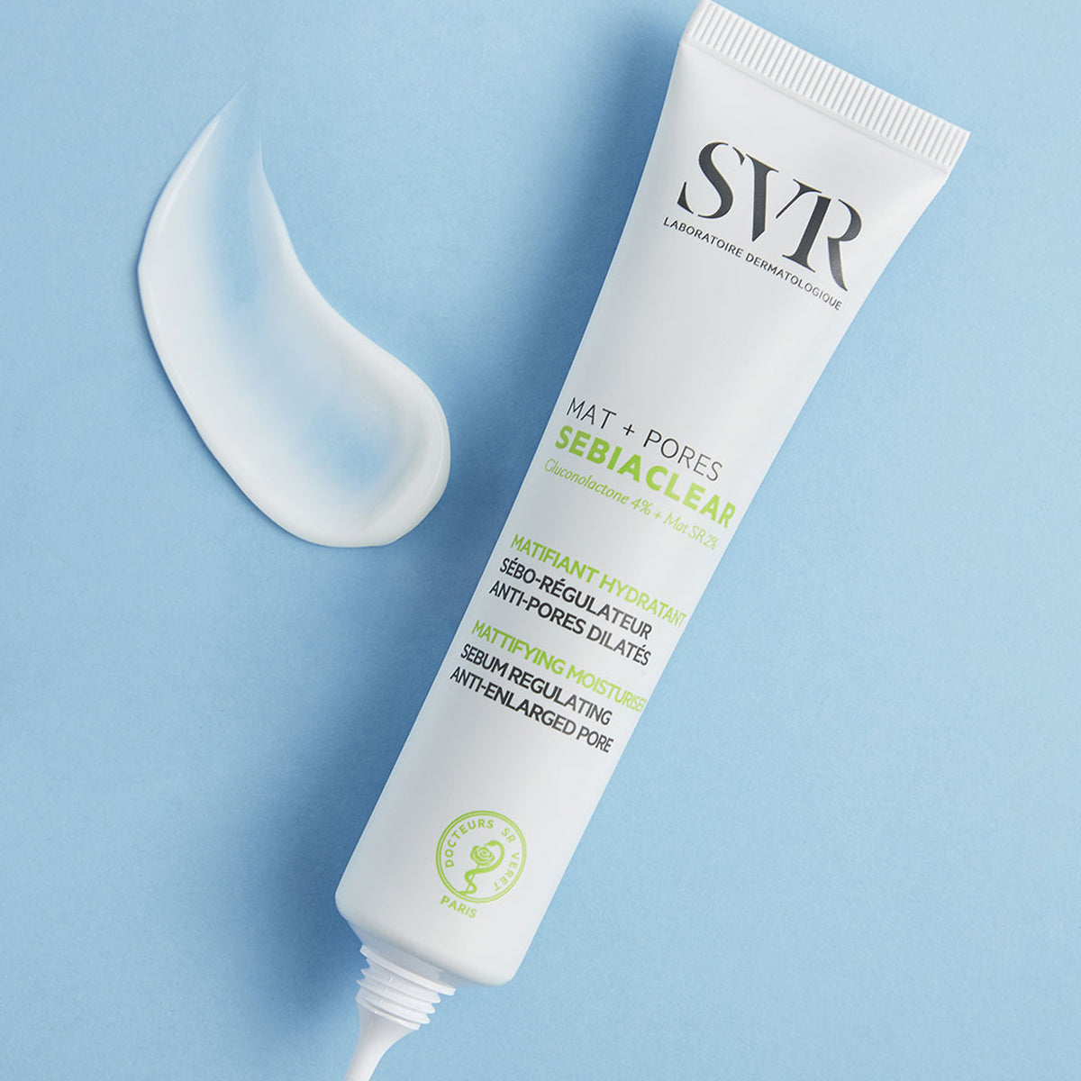 Tubo blanco de SVR Sebiaclear Mat+Pores con textura fluida sobre fondo azul claro.
