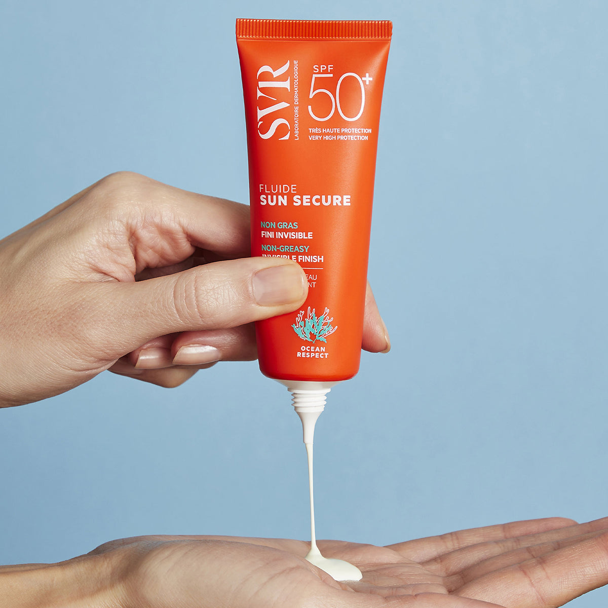 Tubo naranja de protector solar SVR Sun Secure SPF50+ dispensando una textura fluida blanca sobre una mano abierta.