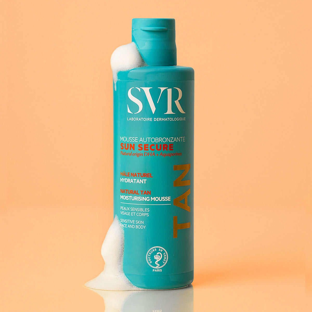 Botella de espuma autobronceadora SVR Sun Secure color turquesa con textura de mousse sobre fondo naranja suave.