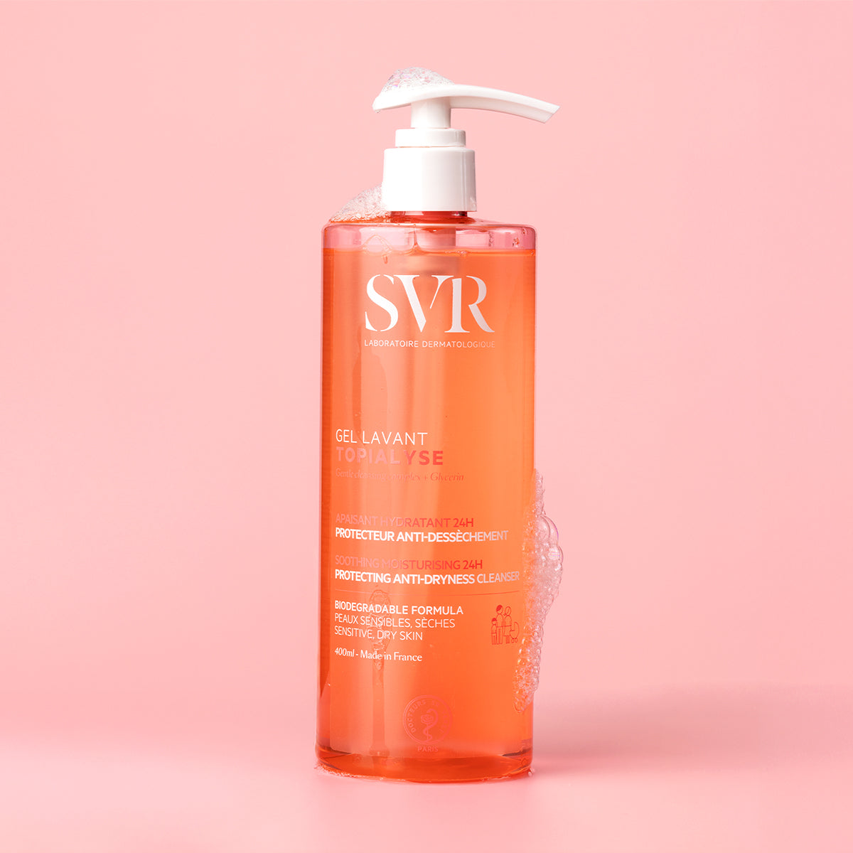 Envase de 400ml de gel limpiador SVR Topialyse con dispensador y espuma sobre fondo rosa suave.