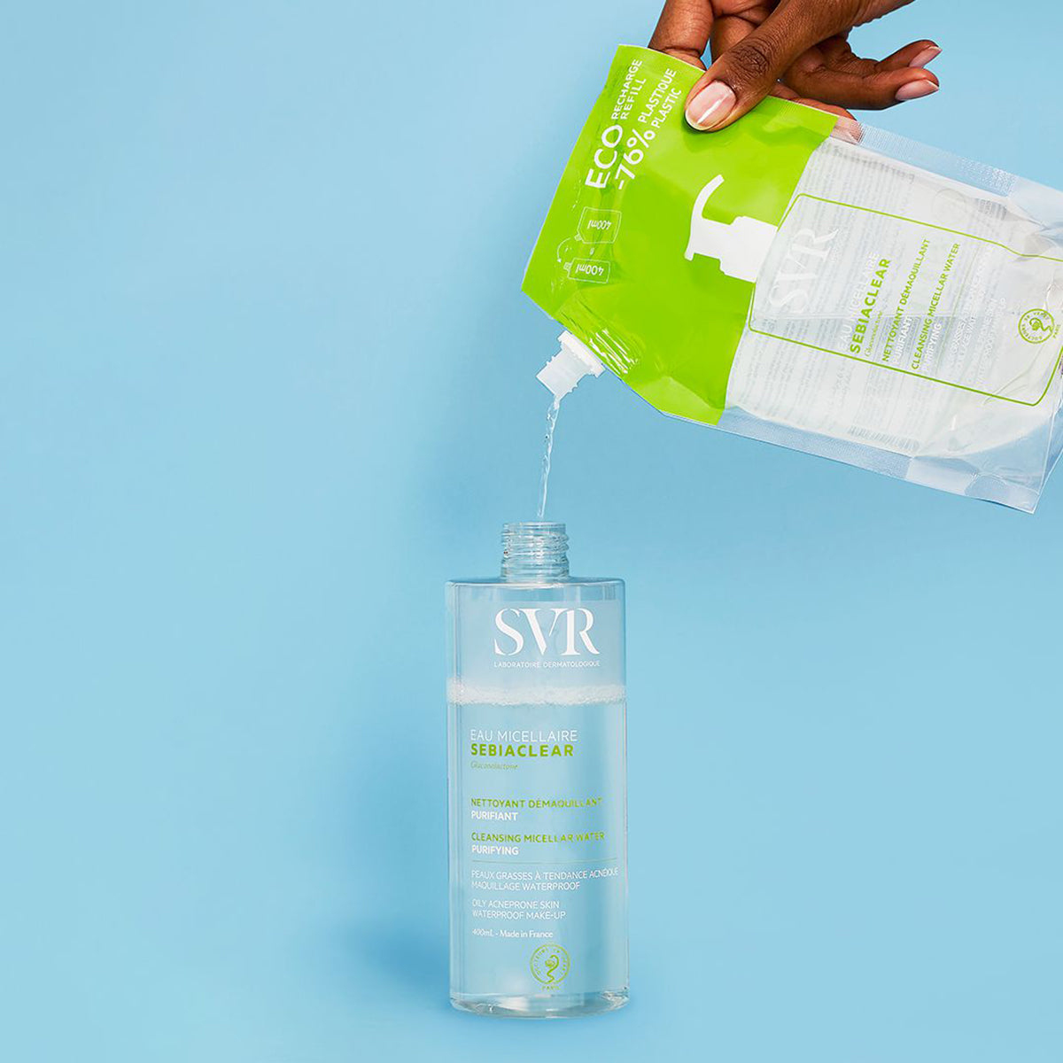Recarga ecológica de SVR Sebiaclear vertiendo agua micelar purificante en un frasco transparente sobre fondo azul.