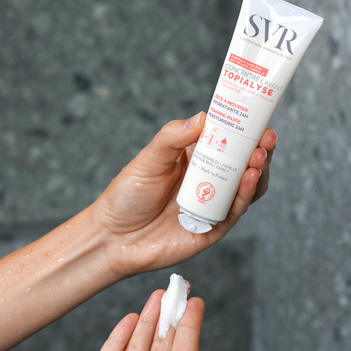 SVR TOPIALYSE Concentré Lavant white squeeze tube dispensing a creamy foaming paste into a hand.