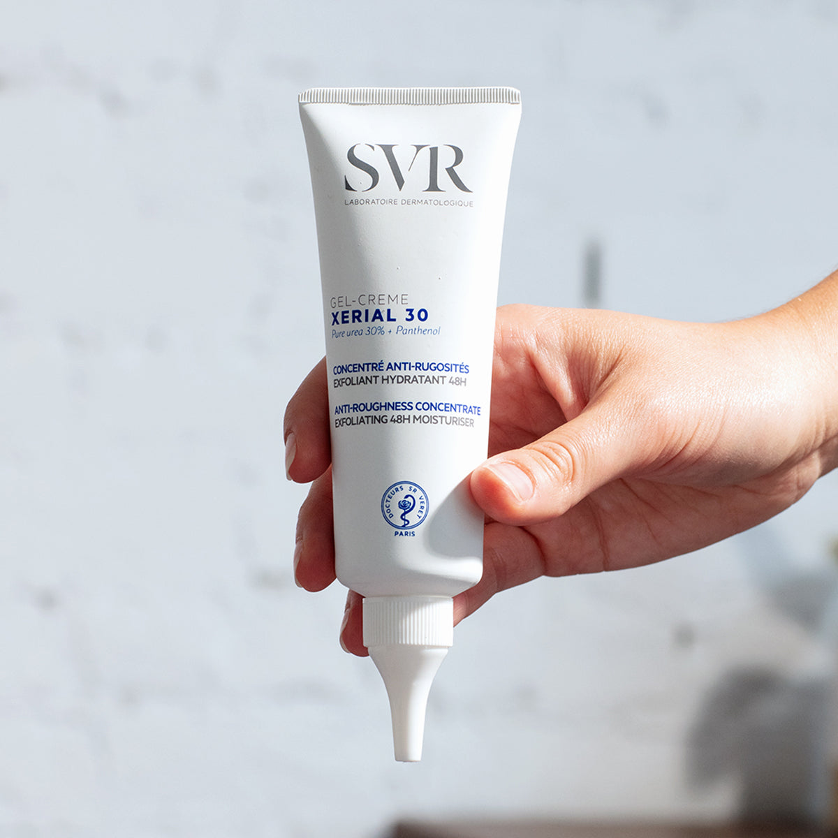 Tubo blanco de SVR XERIAL 30 Gel-Creme sostenido en una mano, mostrando su diseño ergonómico y aplicador de punta fina.