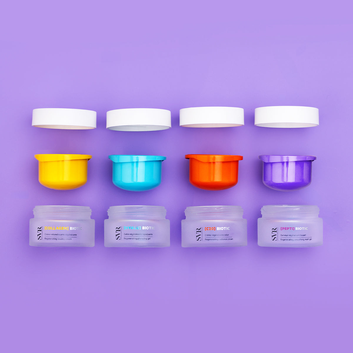 Cuatro frascos de crema SVR Biotic con tapas blancas y bases coloridas sobre un fondo morado.