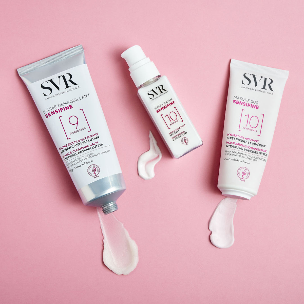 Tres productos SVR Sensifine en envases blancos sobre fondo rosa, con muestras de crema blanca saliendo de los tubos.