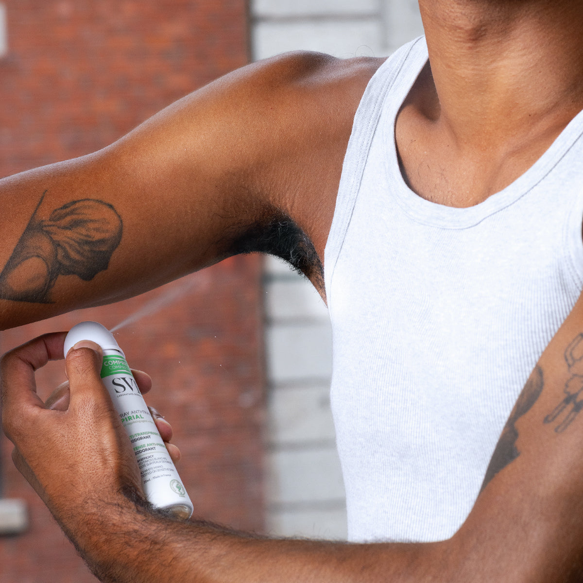 Persona aplicando el spray antitranspirante SVR Spirial comprimido en la axila, con envase blanco y detalles en verde.