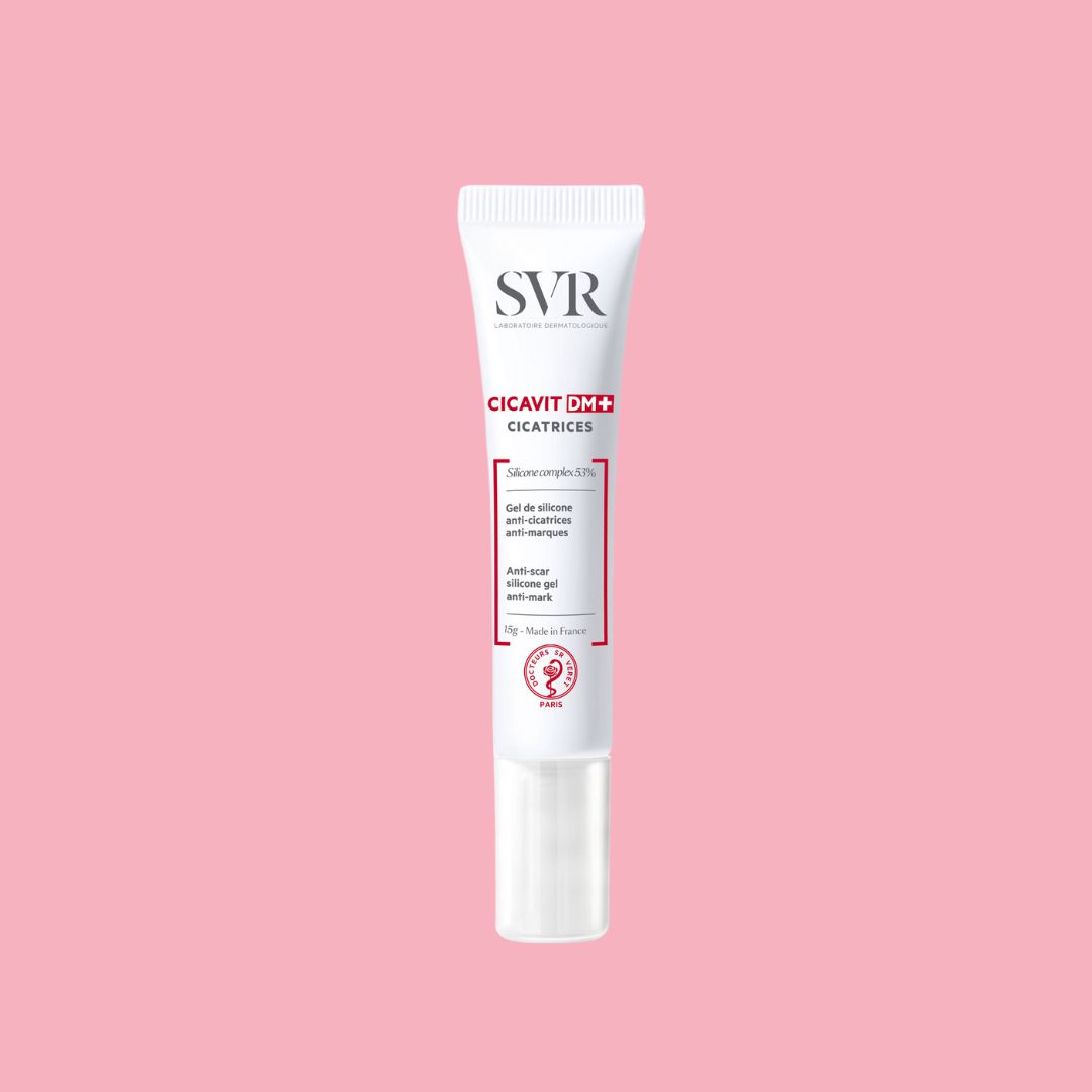 Tubo blanco de gel cicatrizante SVR Cicavit DM+ de 15g con letras rojas y negras sobre un fondo rosa suave.