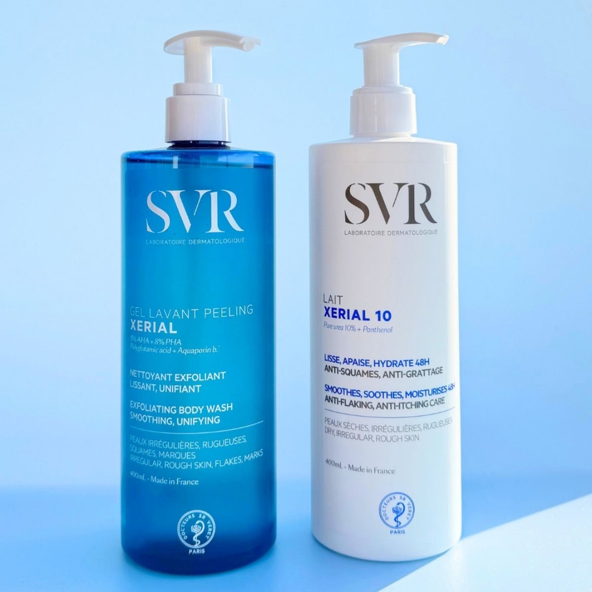 Dos botellas con dispensador SVR: Gel Lavant Peeling azul y Lait Xerial 10 blanco sobre fondo azul claro.