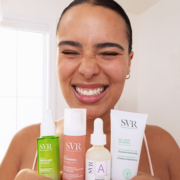 Smiling woman holding four SVR skincare products, including Sebiaclear serum, Palpebral balm, Vitamin A ampoule, and Spirial deodorant.