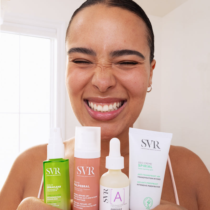 Smiling woman holding four SVR skincare products, including Sebiaclear serum, Palpebral balm, Vitamin A ampoule, and Spirial cream.