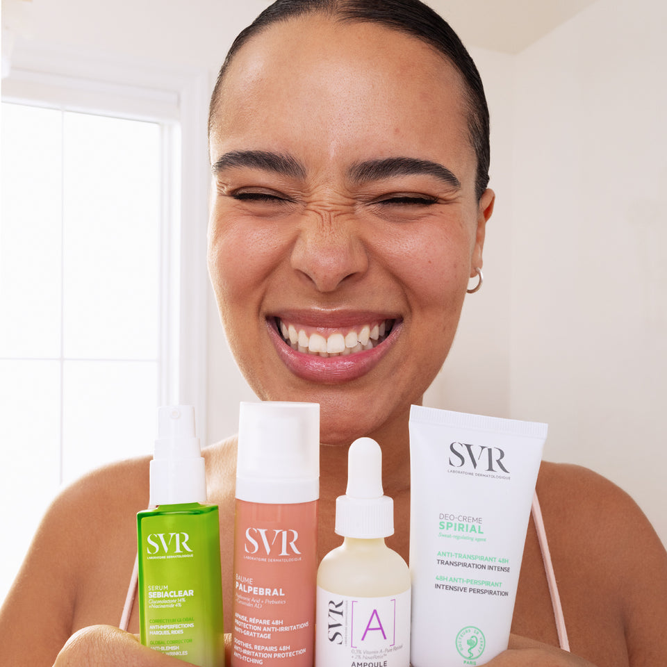 Smiling woman holding four SVR skincare products, including Sebiaclear serum, Palpebral balm, Vitamin A ampoule, and Spirial cream.