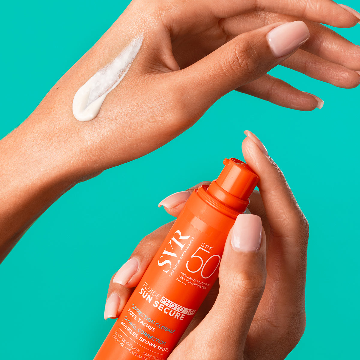 Hands holding an orange SVR SUN SECURE SPF50+ pump bottle with a dab of white sunscreen cream on the skin.